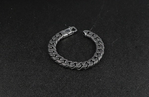 Detailed macro view of engraved snake patterns on a punk style stainless steel curb bracelet