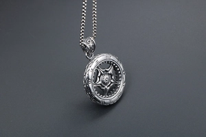 Détail du pendentif roue argentée avec découpe pentagramme et symboles de runes gravés