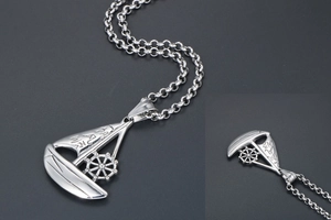 Macro shot of a silver sailboat pendant with engraved Chinese characters and steering wheel