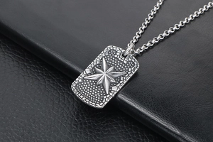 Detail of vintage silver military tag pendant with embossed star on black leather background