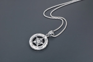 Vue macro détaillée du pendentif roue vintage avec gravure de tournesol sur fond gris foncé