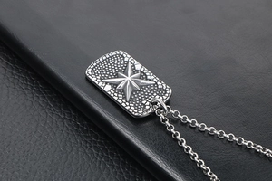 Detail of vintage military dog tag pendant with compass star carving on leather background