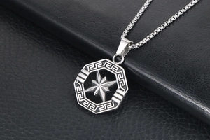 Close-up of silver titanium steel octagon pendant with star relief and Greek key border