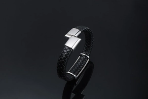 Détail du bracelet en cuir tressé noir avec boucle en métal argenté poli et brillant