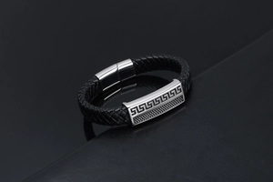 Détail d'un bracelet en cuir tressé noir avec plaque en métal à motif de méandres grecs