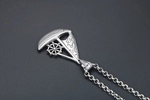 Detailed view of silver sailing ship pendant with engraved Chinese blessing symbols