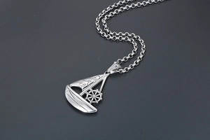 Detailed close-up of a silver sailboat pendant featuring a rotating rudder and engravings