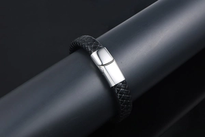 Détail d'un bracelet en cuir tressé noir avec un fermoir magnétique en acier inoxydable poli