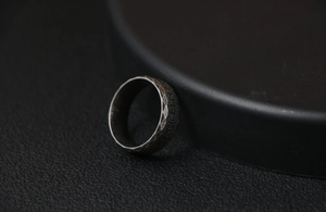 Macro detail of Nordic Viking runes engraved on a hammered vintage titanium steel ring
