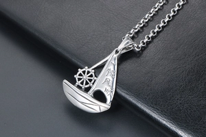 Close-up of silver steel sailing boat pendant with smooth texture and rudder detail