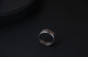 Macro detail of vintage titanium steel ring with Nordic runes and hammered texture