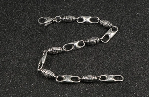 Detailed close-up of stainless steel cylinder link bracelet with lobster clasp on black