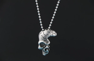 Détail du pendentif crâne argenté avec texture fissurée et finition oxydée vintage