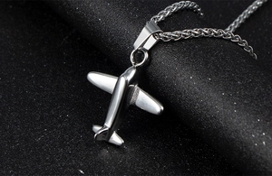 Macro shot of polished silver stainless steel aircraft pendant on wheat chain