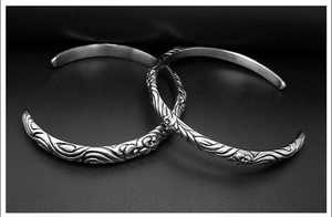 Macro shot of retro silver bangles featuring detailed cross and skull relief patterns