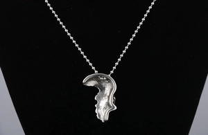 Détail du pendentif crâne argenté avec texture de lave et chaîne à billes en acier
