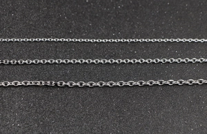 Detailed macro view of three different thickness silver stainless steel O-chains on black surface