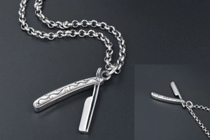 Detailed view of vintage barber razor pendant with intricate floral engravings on a chain