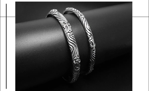 Macro detail of retro silver bangles featuring gothic cross relief and vintage carvings