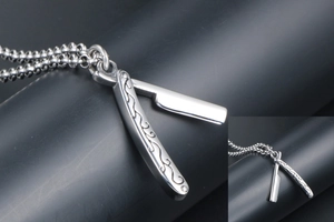 Detailed close-up of a silver razor pendant with intricate vine patterns on the handle