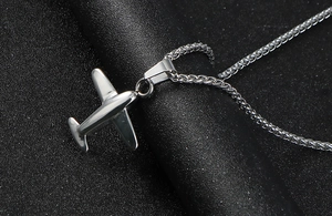 Macro shot of polished stainless steel P51 Mustang aircraft pendant and woven chain links