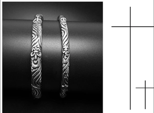 Detailed close-up of retro silver bracelets with cross patterns on a black stand