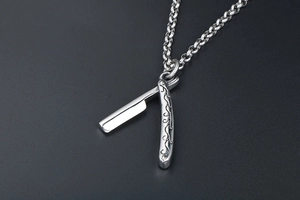 Macro shot of silver folding razor pendant with ornate vintage floral engravings