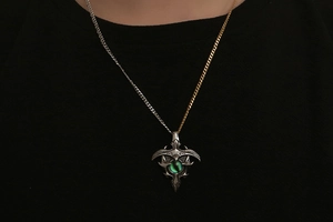 Detail of vintage silver totem pendant with green cat-eye stone on two-tone metal chain