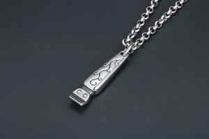 Macro shot of vintage titanium steel hair clipper pendant with engraved floral patterns