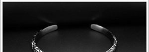 Macro detail of retro cross pattern engraving on a silver open-ended couple's bracelet
