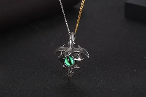 Detail of vintage bird wing necklace with green cat-eye gemstone and two-tone chain