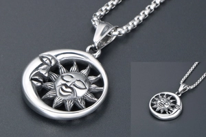 Détail macro du pendentif soleil et lune en argent avec chaîne box sur fond texturé
