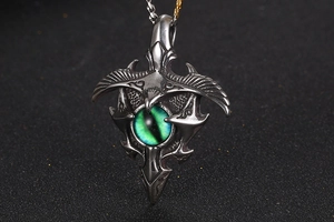 Detailed view of gothic shield eagle pendant with green cat eye stone on dark texture