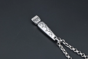 Macro shot of vintage hair clipper pendant with vine engraving and metal chain