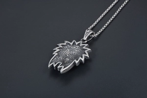 Detail of vintage tribal portrait pendant back with pebble texture and silver box chain