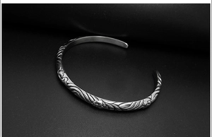 Detail showing vintage totem relief patterns and silver finish on an open cuff bracelet