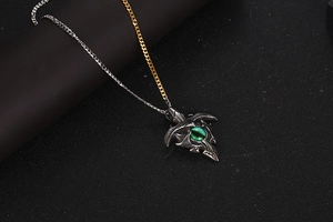 Macro detail of gothic eagle head pendant with green stone on dual-tone chain necklace