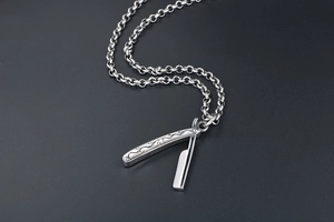 Close-up of retro engraved razor blade pendant on a sturdy steel rolo chain