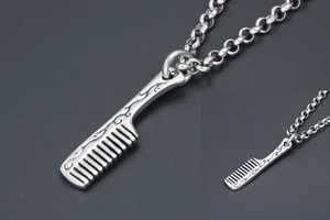 Macro view of comb-shaped pendant with intricate vine engravings on a link chain