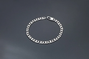 Détail d'un bracelet gourmette en métal argenté poli avec un fermoir mousqueton sûr