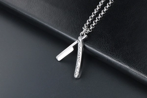 Detailed view of silver barber razor pendant with ornate floral pattern engraving on leather