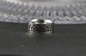 Détail macro d'une bague en acier argenté avec motif de toile d'araignée noire