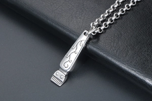 Macro shot of titanium steel hair clipper pendant with intricate engraved floral patterns