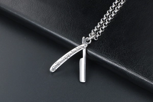 Detailed close-up of a silver straight razor pendant with vintage handle engravings