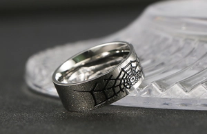Détail d'une bague en acier titane avec motif toile d'araignée noire style gothique
