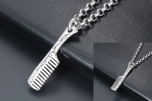 Macro view of silver comb pendant necklace with detailed vine engravings on black leather