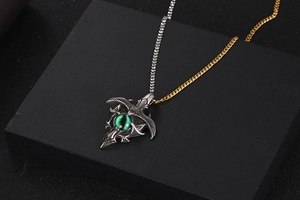 Detail of mixed-metal Cuban chain with vintage silver pendant and green eye gemstone