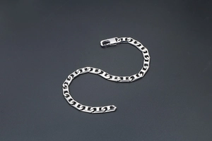 Gros plan d'un bracelet gourmette en argent poli avec un fermoir mousqueton solide