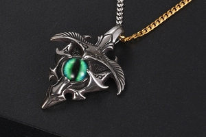 Macro shot of silver devil eye pendant with green stone and two-tone Cuban chain