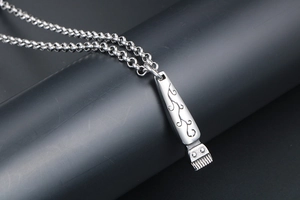 Detailed macro shot of a silver hair clipper pendant with vine engravings and O-link chain